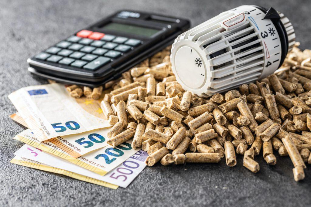 Ecological heating. Wooden pellets, euro banknotes, calculator and thermostatic head.
